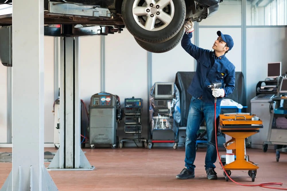 Perito revisando los bajos de una camioneta 4x4 levantada inspeccionando diferencial y cardán